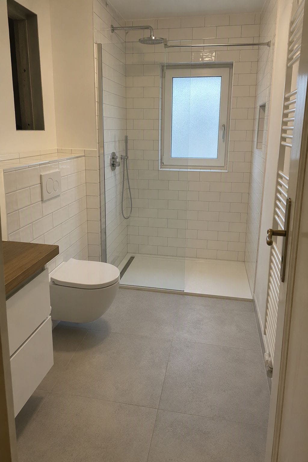 Bodengleiche Dusche mit Glasabtrennung und weißen Subway-Fliesen.